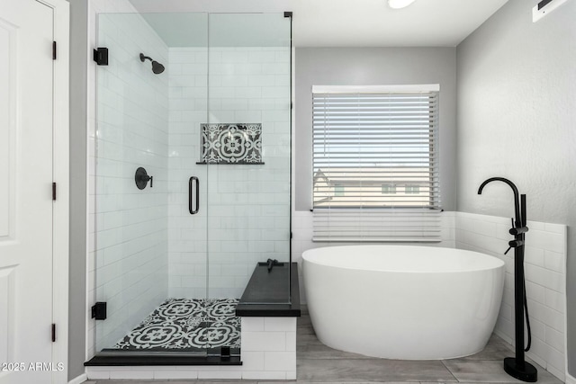 full bathroom featuring tile walls, a freestanding bath, and a shower stall