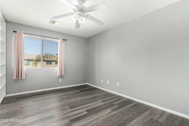 empty room featuring a ceiling fan, wood finished floors, visible vents, and baseboards