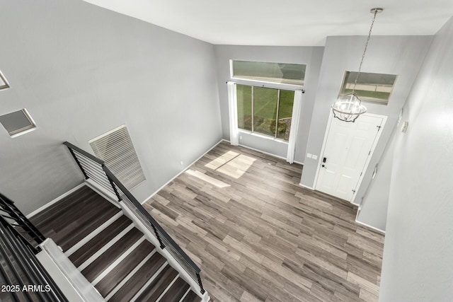 foyer entrance featuring baseboards, visible vents, and wood finished floors