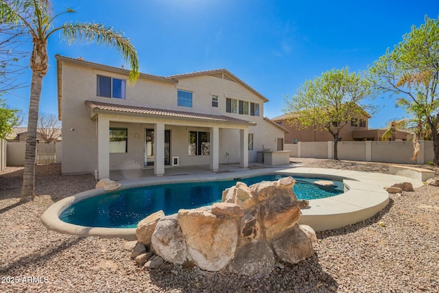 rear view of house with a fenced in pool, stucco siding, a patio area, a fenced backyard, and a tiled roof