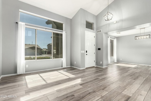 spare room with baseboards, visible vents, a notable chandelier, and wood finished floors