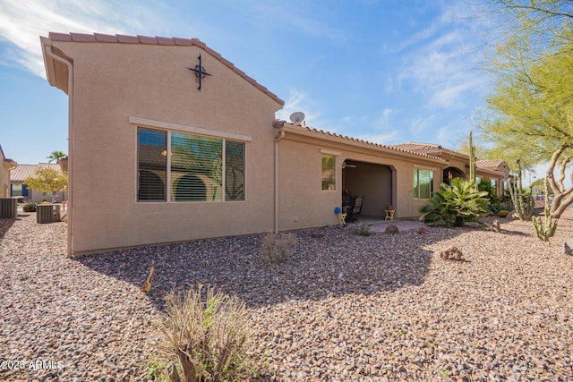 back of house with a tile roof and stucco siding