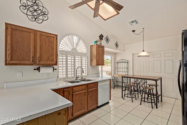 kitchen featuring white dishwasher, a sink, a ceiling fan, brown cabinetry, and light tile patterned flooring