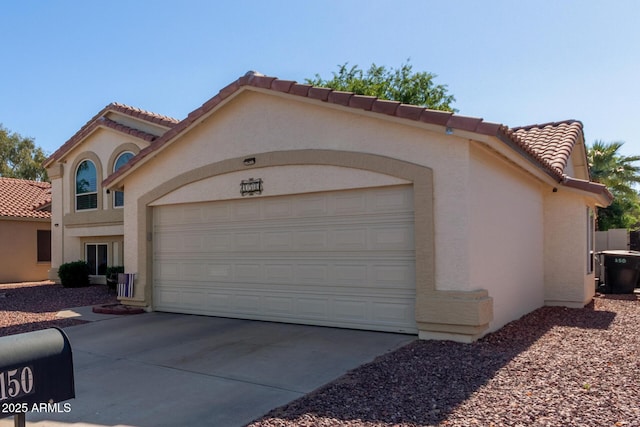 view of front of property with an attached garage, a tiled roof, stucco siding, and driveway