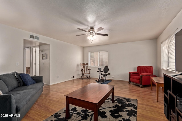 living room with ceiling fan, light wood-style floors, and baseboards