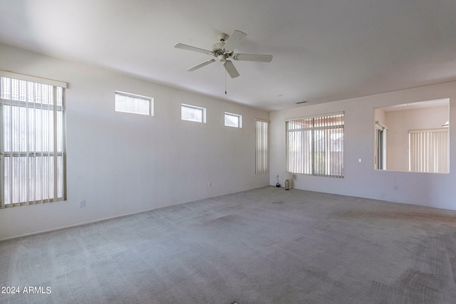 unfurnished room with ceiling fan, carpet flooring, and a wealth of natural light