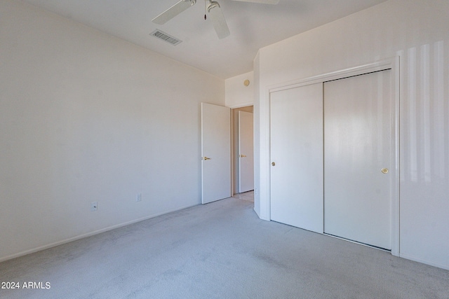 unfurnished bedroom with light carpet, ceiling fan, and a closet