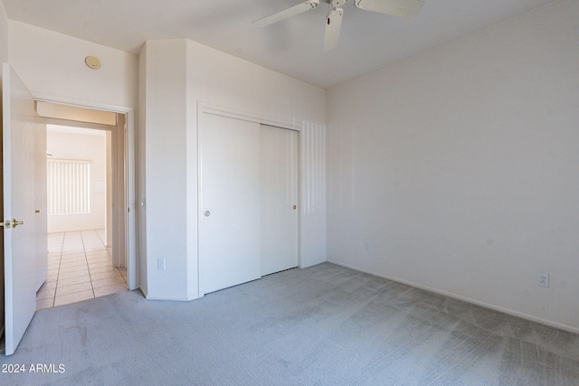 unfurnished bedroom with ceiling fan, a closet, and light carpet