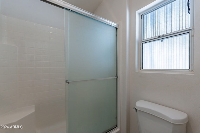 bathroom with a shower with shower door and toilet