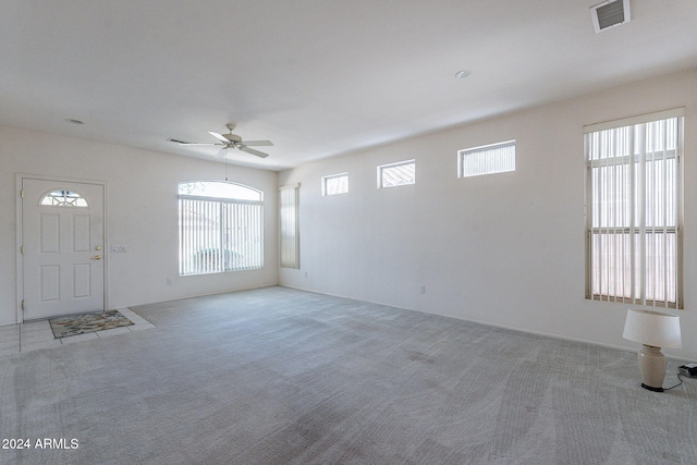 unfurnished living room with ceiling fan, light carpet, and plenty of natural light