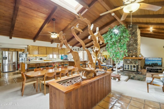 kitchen featuring beam ceiling, a skylight, a fireplace, and stainless steel refrigerator with ice dispenser