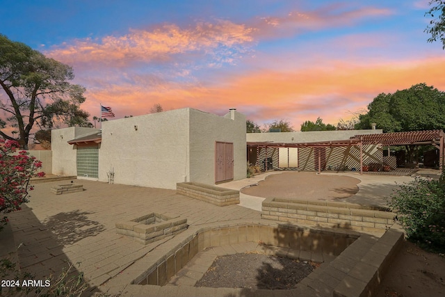 back house at dusk with a patio area and a pergola