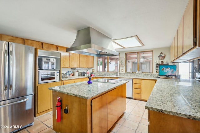 kitchen with light tile patterned flooring, light stone countertops, range hood, appliances with stainless steel finishes, and a kitchen island