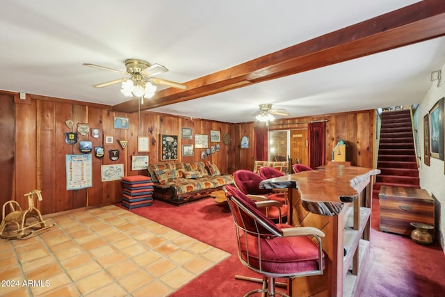 carpeted living room with beamed ceiling, ceiling fan, and wooden walls