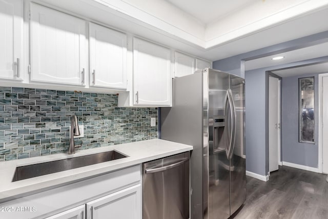 kitchen with appliances with stainless steel finishes, dark hardwood / wood-style floors, tasteful backsplash, white cabinets, and sink