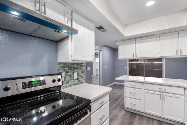 kitchen with stainless steel electric range, decorative backsplash, white cabinetry, and light hardwood / wood-style flooring