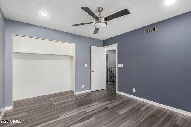 unfurnished bedroom with ceiling fan, dark wood-type flooring, a textured ceiling, and a closet