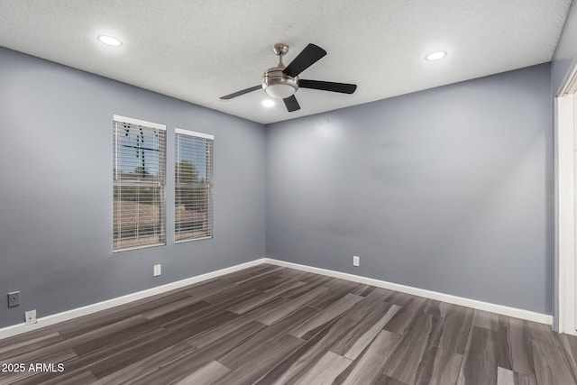 empty room featuring ceiling fan, dark wood-type flooring, and a textured ceiling