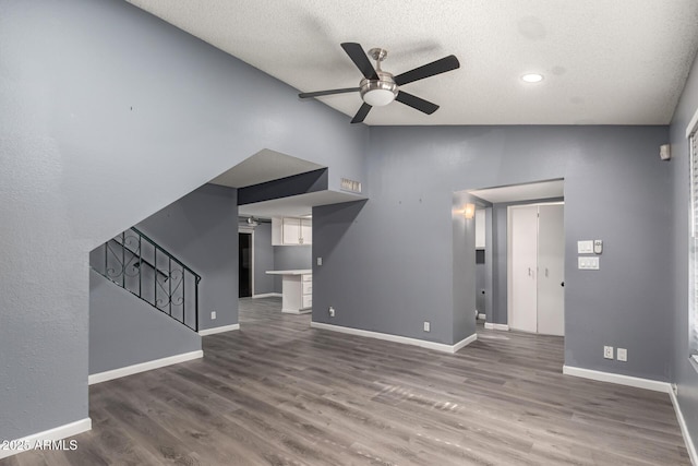 unfurnished living room featuring ceiling fan, a textured ceiling, dark hardwood / wood-style floors, and lofted ceiling