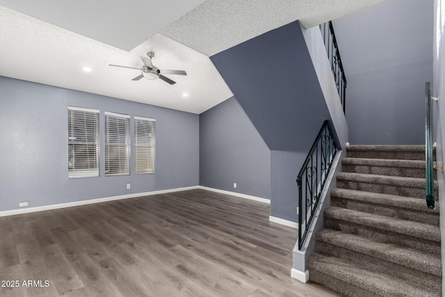 stairs with ceiling fan, a textured ceiling, and hardwood / wood-style flooring