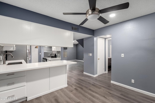 kitchen featuring electric stove, white cabinets, kitchen peninsula, and sink