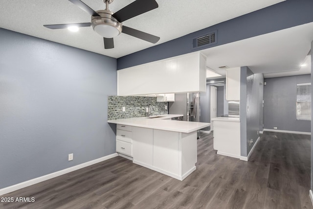 kitchen featuring kitchen peninsula, stainless steel refrigerator with ice dispenser, sink, white cabinetry, and a textured ceiling