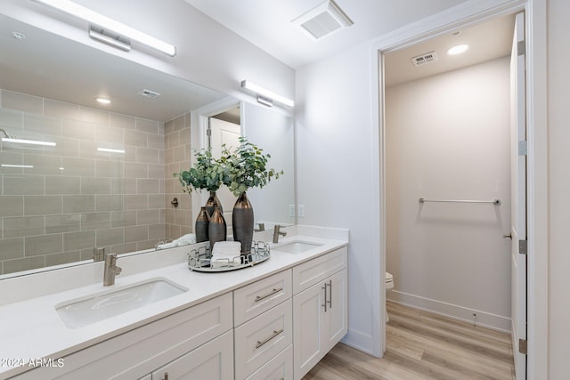 bathroom featuring tiled shower, toilet, vanity, and hardwood / wood-style flooring