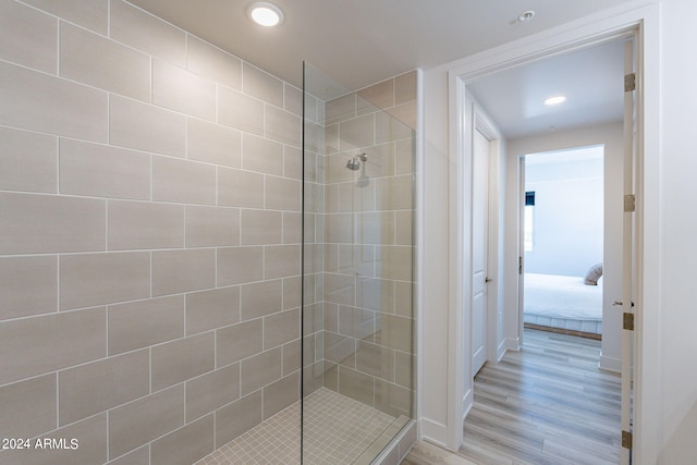 bathroom featuring tiled shower and wood-type flooring