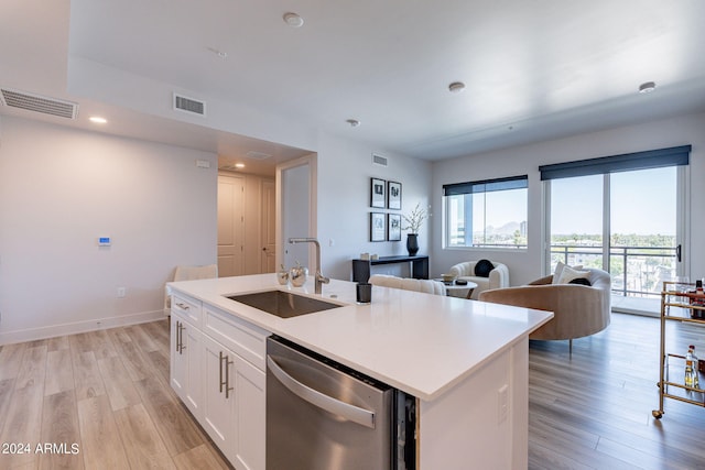 kitchen featuring sink, stainless steel dishwasher, an island with sink, light hardwood / wood-style floors, and white cabinetry