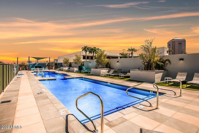 pool at dusk with a patio area