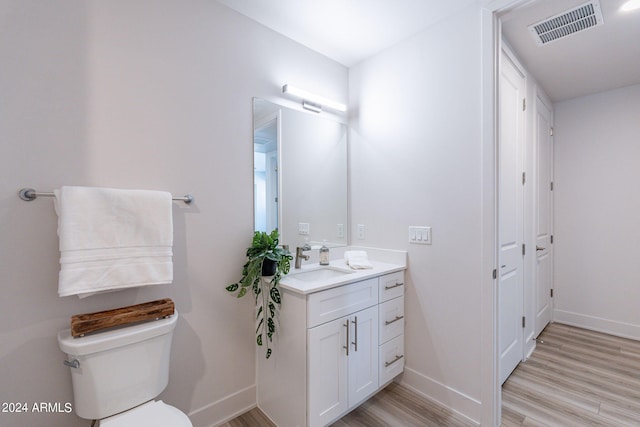 bathroom with hardwood / wood-style floors, vanity, and toilet