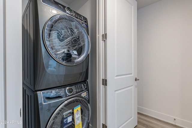 laundry room featuring hardwood / wood-style floors and stacked washer / drying machine