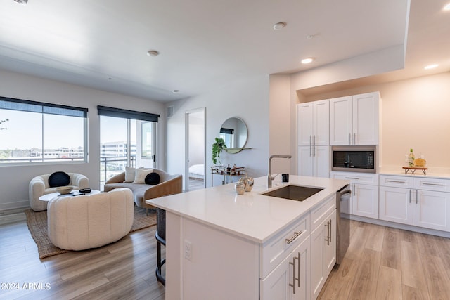 kitchen featuring light wood-type flooring, black microwave, sink, dishwasher, and white cabinets