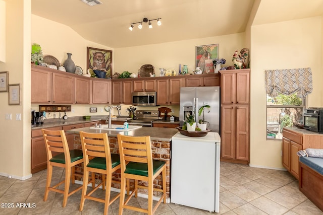 6031 N Milano Ct, Litchfield Park, AZ 85340 - kitchen featuring stainless steel appliances, a sink, a center island with sink, lofted ceiling, and light tile patterned flooring