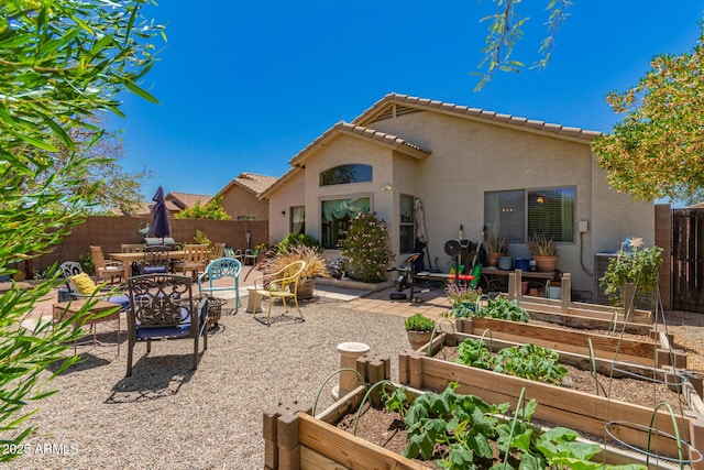 6031 N Milano Ct, Litchfield Park, AZ 85340 - back of house featuring a vegetable garden, stucco siding, fence, a tile roof, and a patio area
