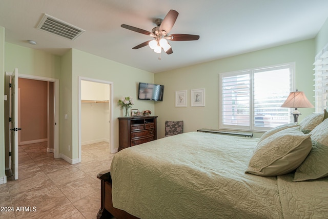 bedroom with ceiling fan, light tile patterned flooring, a walk in closet, and a closet