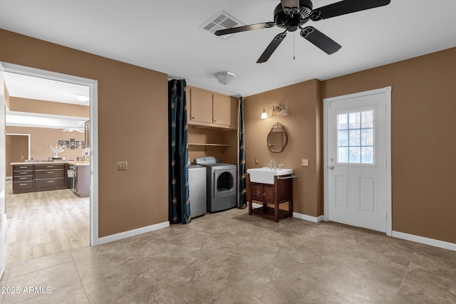 laundry room featuring sink, washing machine and dryer, cabinets, and ceiling fan