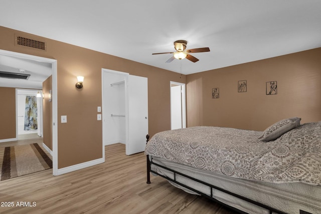 bedroom featuring a spacious closet, light hardwood / wood-style flooring, ceiling fan, and a closet