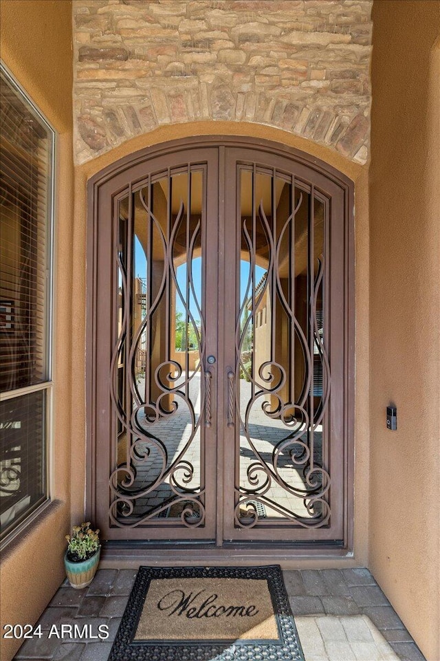 view of exterior entry featuring french doors and stucco siding