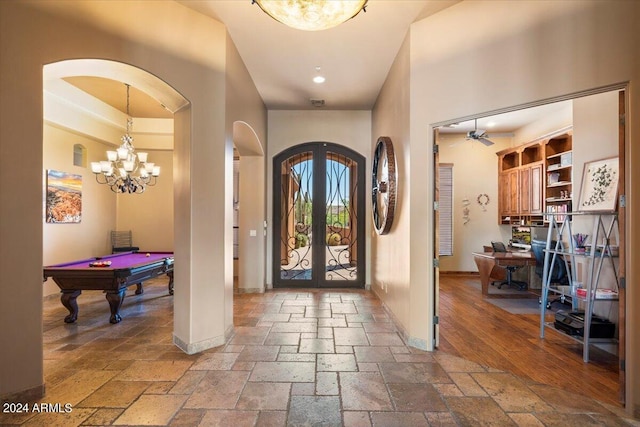 foyer featuring arched walkways, stone tile flooring, baseboards, and an inviting chandelier