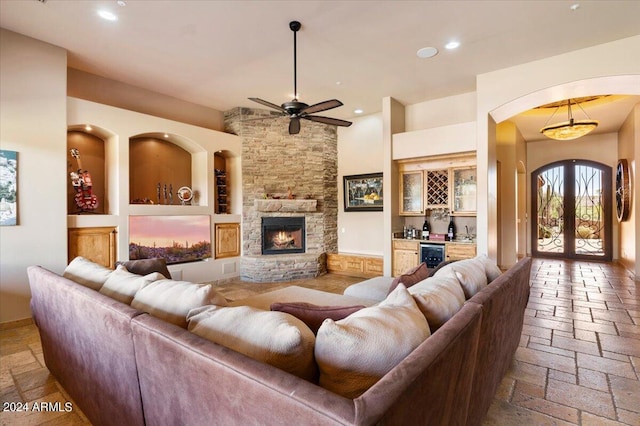 living room featuring recessed lighting, stone tile flooring, a fireplace, and a dry bar