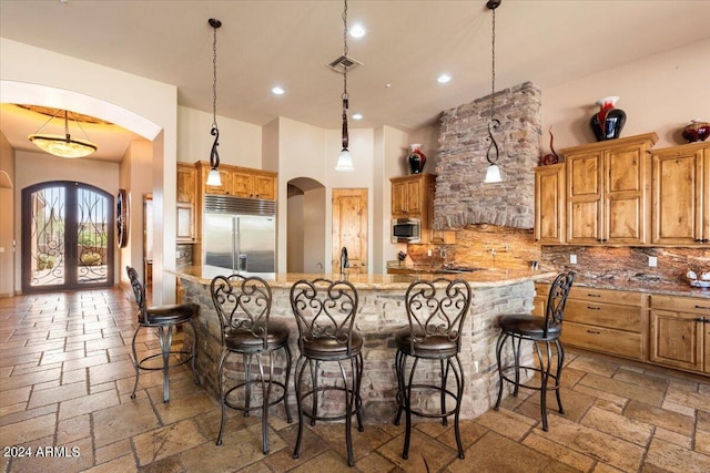 kitchen featuring brown cabinetry, stone tile floors, appliances with stainless steel finishes, and arched walkways