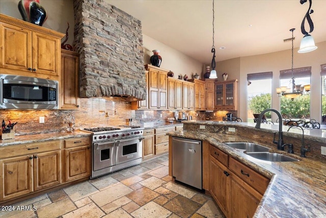 kitchen featuring brown cabinets, tasteful backsplash, stone tile flooring, appliances with stainless steel finishes, and a sink