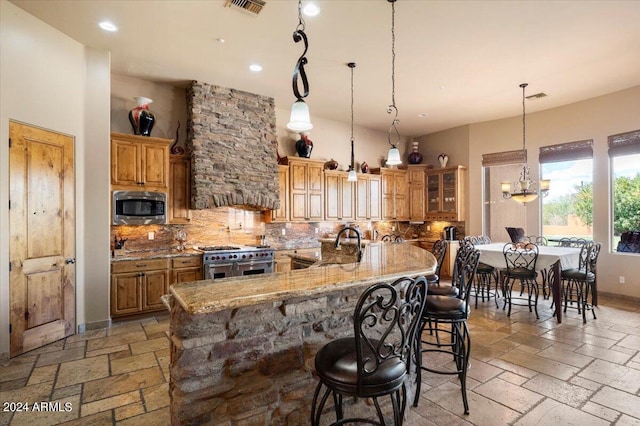 kitchen featuring stainless steel appliances, brown cabinetry, and stone tile floors