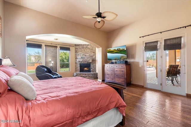 bedroom featuring a fireplace, a ceiling fan, baseboards, access to outside, and wood-type flooring