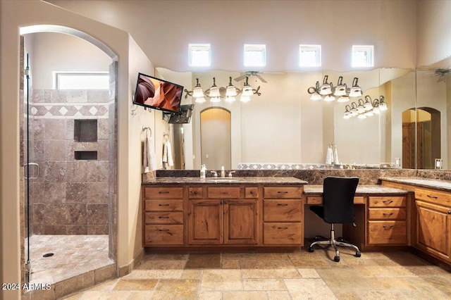 full bath with a stall shower, stone tile floors, and vanity