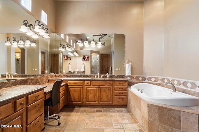 full bath with stone tile floors, a high ceiling, ceiling fan, vanity, and a bath