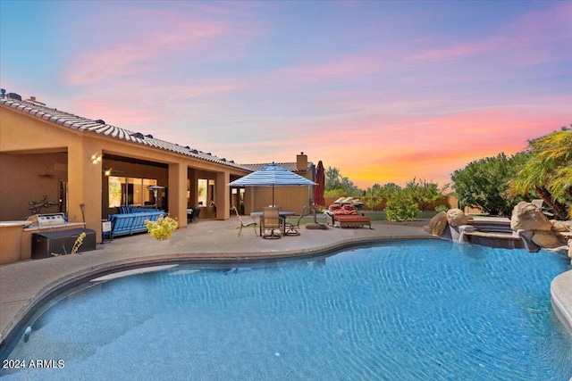 pool at dusk featuring a patio area, an outdoor hangout area, and an outdoor pool