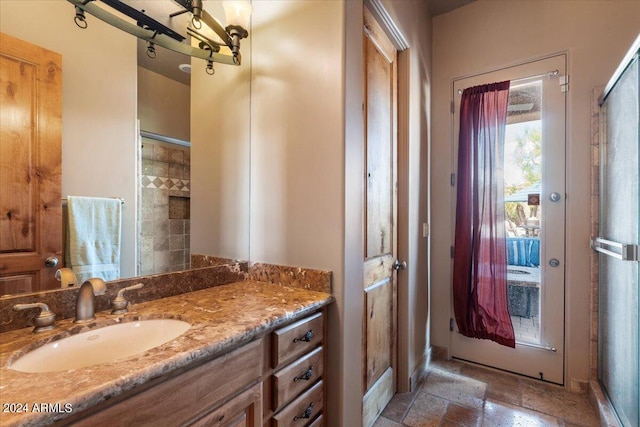 full bath with stone finish flooring, walk in shower, and vanity