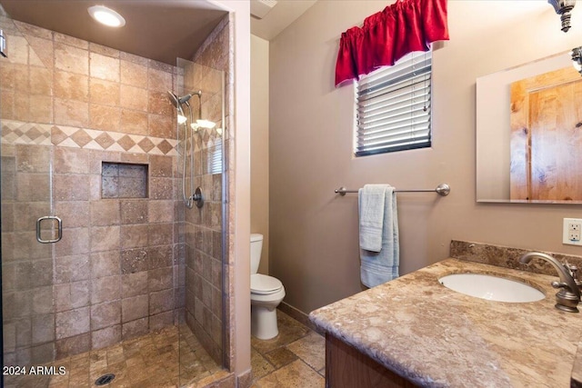 bathroom with toilet, a stall shower, stone tile floors, and vanity